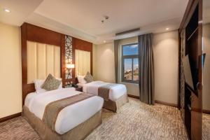 艾卜哈Sarwat Park Hotel的酒店客房设有两张床和窗户。