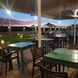 Agios AvgoustinosHotel Sias Resort的餐厅设有绿色的桌椅,享有日落美景