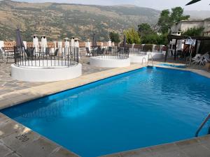 布维翁Acogedor Apartamento - La Alpujarra的蓝色的游泳池,带椅子,山底下