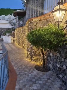 伊斯基亚L'Incanto Suites Ischia的石墙,有树和街灯