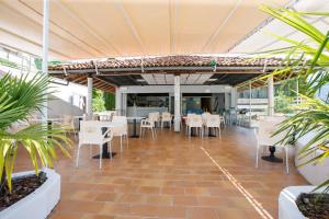吉法Studio-Apartments La Selva的一间设有白色桌椅的餐厅,种植了植物