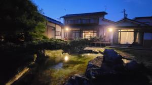 Kurita1日1組限定 プライベート空間 古民家貸切コテージとけい的夜晚在房子前面有一个池塘