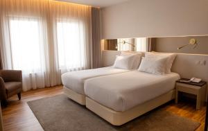 塞图巴尔Hotel Cristal Setúbal的卧室配有一张白色大床和一把椅子