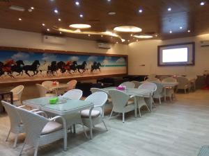 阿吉曼Corniche Palace Hotel的一间带桌椅和屏幕的用餐室