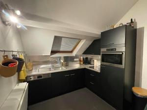 杜柏Escape at Durbuy的一间小厨房,配有黑色橱柜和水槽