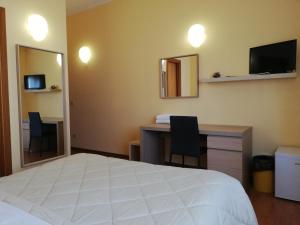 兰恰诺罗马酒店的一间卧室配有一张床、一张书桌和一面镜子