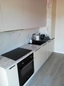 贡斯基Apartament Latarnik- Yellow的厨房配有白色橱柜和黑炉灶烤箱。