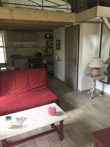 Coulonges-sur-lʼAutizeLa Remise的客厅配有红色的沙发和桌子