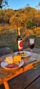 卡兰卡斯Pousada Canto da Lua - charme e vista incrível的一瓶葡萄酒和一张木桌上的玻璃杯