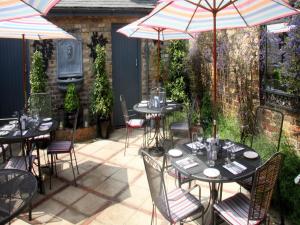 温莎Gilbey's Bar, Restaurant & Townhouse的一个带桌椅和遮阳伞的庭院。