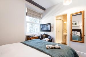 安布尔塞德诺伍德豪斯旅馆的一间卧室配有一张床、一张书桌和一面镜子