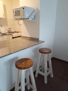 布宜诺斯艾利斯Parque Patricios 2 ambientes的两个凳子坐在厨房柜台,配有微波炉