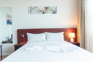 达累斯萨拉姆Pauraque Soho Hotel的卧室配有白色的床和木制床头板