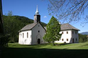 ArriachKlösterle Haus Egon的一座古老的白色教堂,在绿地中陡峭
