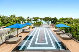 芭堤雅市中心Mera Mare Pattaya的一个带椅子和蓝伞的游泳池