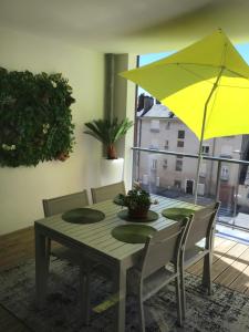 罗德兹Rodez Aveyron appart. T4 neuf 2 places parking的一张带黄伞的餐桌