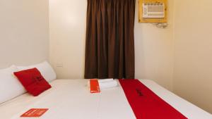 马尼拉RedDoorz near EDSA Camp Crame的一间卧室配有一张带红色枕头的床和一扇窗户