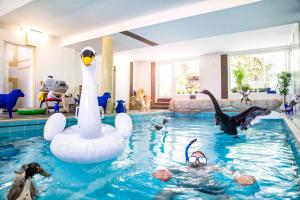 埃尔克拉特Gartenhotel Fettehenne的一座房子里拥有天鹅和天鹅的游泳池