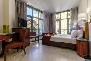 巴塞罗那EXE莱塔纳皇宫酒店的配有一张床、一张书桌和一扇窗户的酒店客房