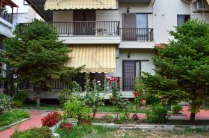 帕拉塔蒙Manos Kritikakis Apartments的一座花园,位于一座种有树木和鲜花的建筑前