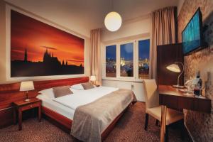 布拉格Metropolitan Old Town Hotel - Czech Leading Hotels的一间卧室配有一张床、一张书桌和一个窗户。