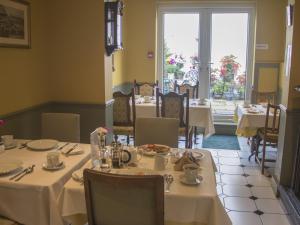 伊斯特布恩Albert & Victoria Guest House的餐厅设有白色的桌椅和窗户。