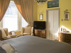 伊斯特布恩Albert & Victoria Guest House的一间卧室设有一张床、一台电视和一个窗口。
