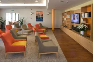 奥尔泰兹Domitys Les Clés d'Or的一间配备有橙色和灰色椅子及电视的等候室