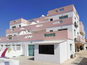 XylophaghouLarnaca Xylophagou 2-bedroom apartment with a shaded terrace的粉红色和白色的建筑,设有大窗户