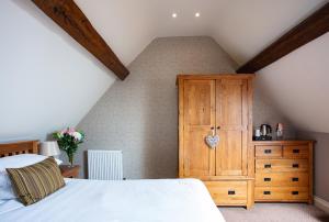 埃文河畔斯特拉特福Broom Hall Inn的一间卧室配有一张床和一个木制橱柜
