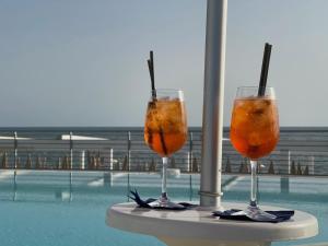 庞特卡格纳诺Blu Hotel的坐在泳池旁的桌子上喝两杯饮料