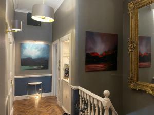 爱丁堡Ben Cruachan Guest House的走廊上墙上有两幅画作,还有一面镜子