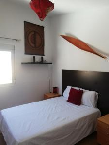 阿尔戈多纳莱斯Atico centrico ideal en Algodonales的一间卧室配有带白色床单和红色枕头的床。