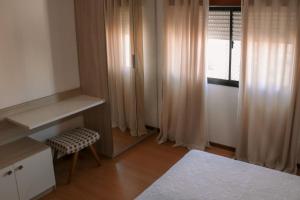 帕苏丰杜Belo Apartamento Central Master Collection的一间卧室配有一张床、一张书桌和一个窗户。