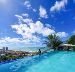 马塞约Pousada Paradise Vista do Atlantico的坐在无边游泳池中的女人,欣赏海景