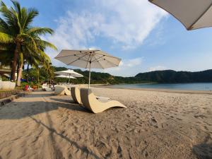 纳苏格布Pico de Loro Staycation (3 beds- 6 pax)的海滩上的一排椅子和一把遮阳伞