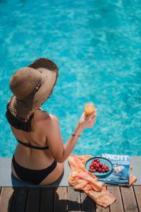 费特希耶Avilia Suites的戴帽子的女人在泳池旁喝一杯