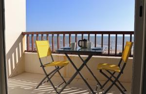 圣让-德蒙Studio Front de Mer的阳台配有两张黄色椅子和一张桌子
