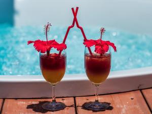 石垣岛ザ・ビーチテラスホテルアオ石垣的两杯鸡尾酒,桌上放着红色鲜花