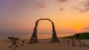 石垣岛ザ・ビーチテラスホテルアオ石垣的海滩上的木拱,背面是日落