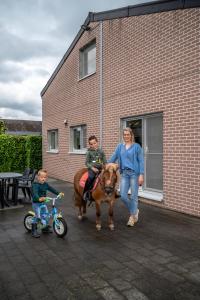 NeerpeltHoevetoerisme Op 't Zand的一名妇女和两名儿童,一名骑着马和自行车的妇女