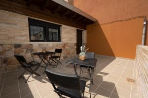 纳瓦莱诺Hotel Rural La Casa de Mis Abuelos的一个带两张桌子和椅子的庭院,毗邻墙壁