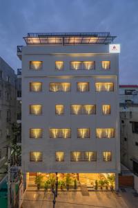 海得拉巴SKYLA Serviced Apartments & Suites, Hi-Tech City的黄昏时分有窗户的高大的白色建筑