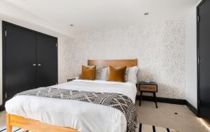 伦敦The Wapping Wharf - Modern & Bright 2BDR Flat on the Thames with Parking的一间卧室配有一张大床和木制床头板