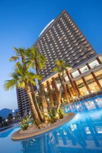 贝尼多姆Hotel BCL Levante Club & Spa 4 Sup - Only Adults Recomended的一座棕榈树环绕的大建筑,位于游泳池前
