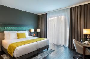 多特蒙德Leonardo Hotel Dortmund的一间卧室配有一张大床和一张书桌