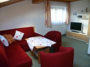 阿布特瑙Apartement Obweghof Abtenau, Salzburger Land的客厅配有2把红色椅子和电视