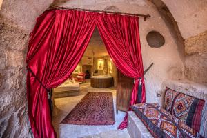 内夫谢希尔Cappadocia Eagle Cave Inn的石头建筑中一间设有红色窗帘的房间