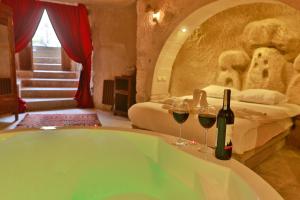 内夫谢希尔Cappadocia Eagle Cave Inn的一间带浴缸及两杯葡萄酒的浴室