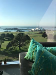 马德普拉塔Incomparable Vista al Golf的沙发,坐在窗户前,享有美景